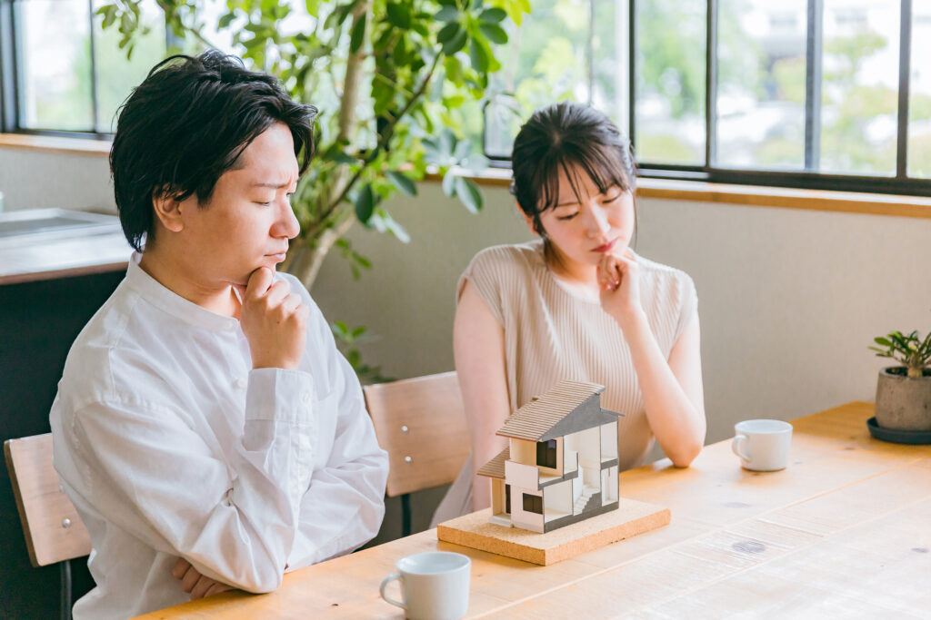 家の模型を見て悩む男女
